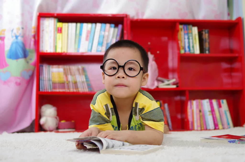 Enfant lisant un livre allongé au sol dans une bibliothèque colorée