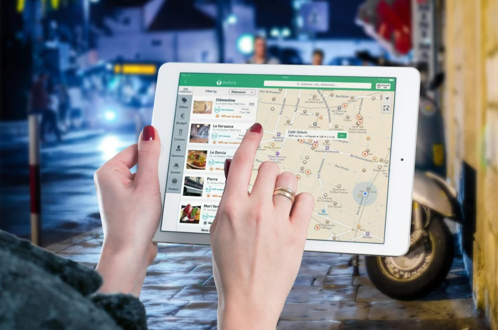 Recherche de restaurants sur carte interactive via tablette. - iterates Femme utilisant une tablette pour chercher un restaurant sur une application de carte interactive.