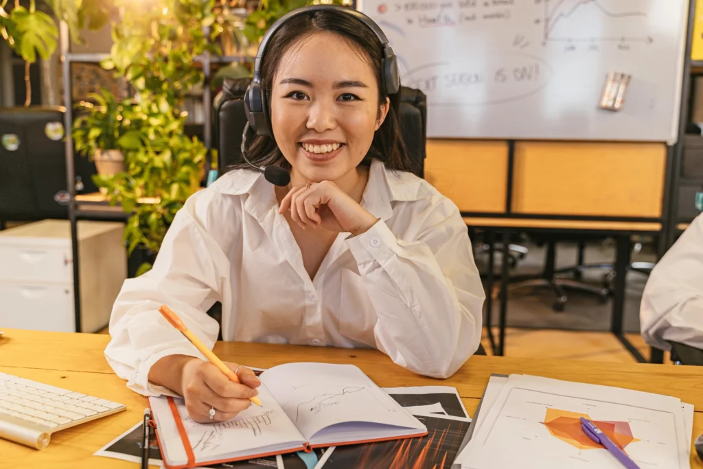 Analyse de données en visioconférence. - iterates Femme souriante avec casque micro travaillant sur des graphiques dans un bureau.
