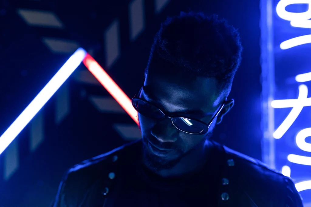 Homme portant des lunettes de soleil dans une ambiance lumineuse bleue avec des néons.