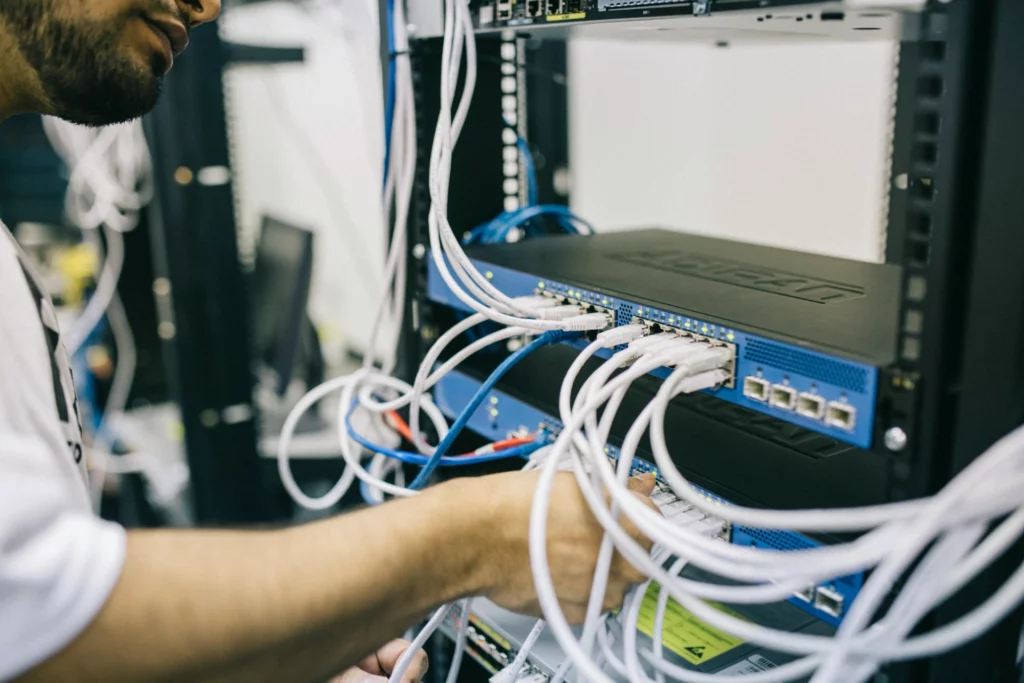 Installation et maintenance de réseau informatique - iterates Technicien connectant des câbles réseau dans un serveur informatique.