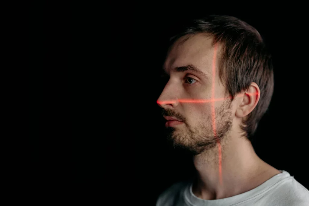 Analyse biométrique du visage par scan laser. - iterates Reconnaissance faciale avec projection de lignes laser rouges sur le visage d’un homme.