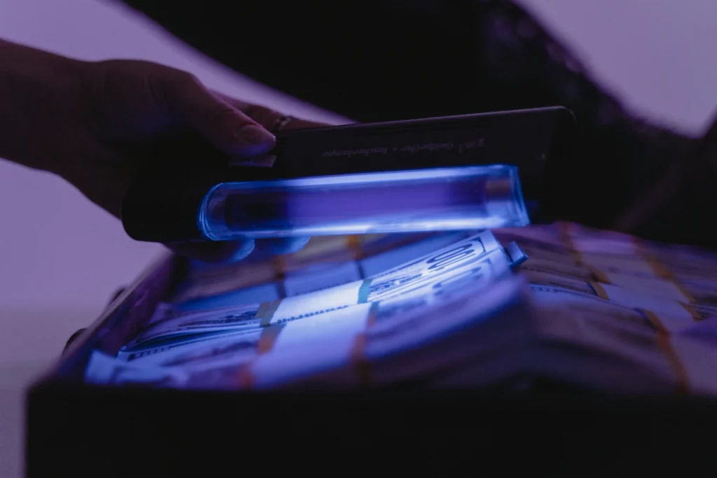 Contrôle de faux billets avec lampe UV. - iterates Vérification de billets de banque sous lumière ultraviolette.