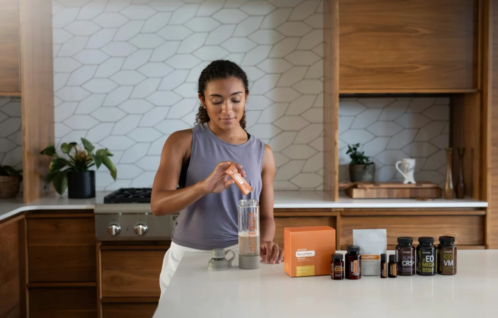 Préparation de boisson santé avec des produits doTERRA MetaPWR - iterates Femme préparant une boisson bien-être avec des compléments alimentaires.