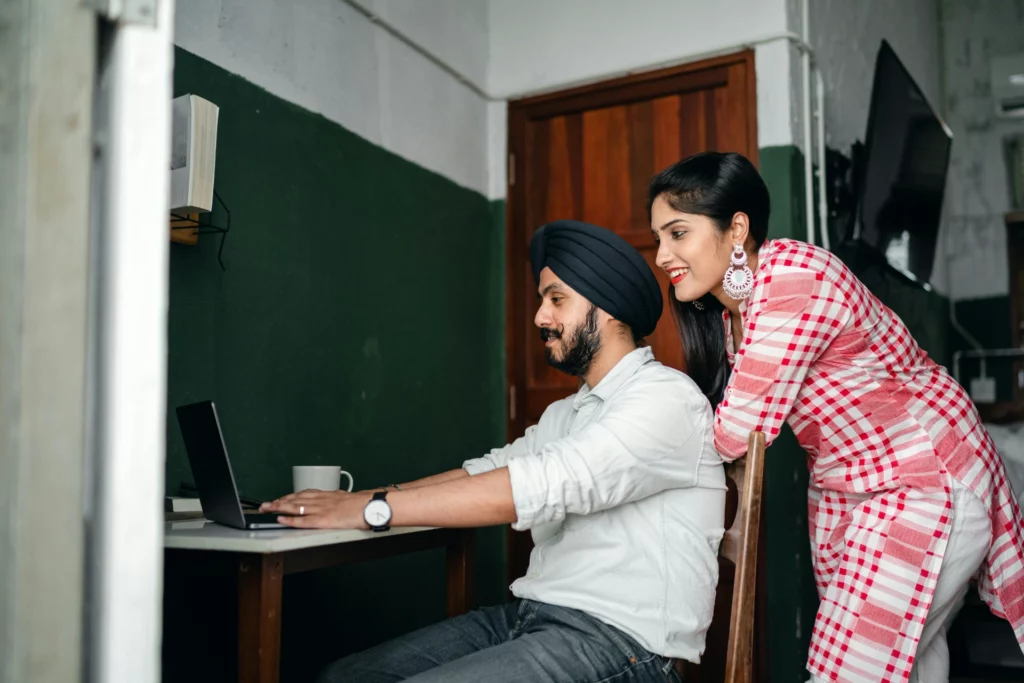 Travail collaboratif à domicile en couple - iterates Couple souriant utilisant un ordinateur portable dans un cadre domestique.