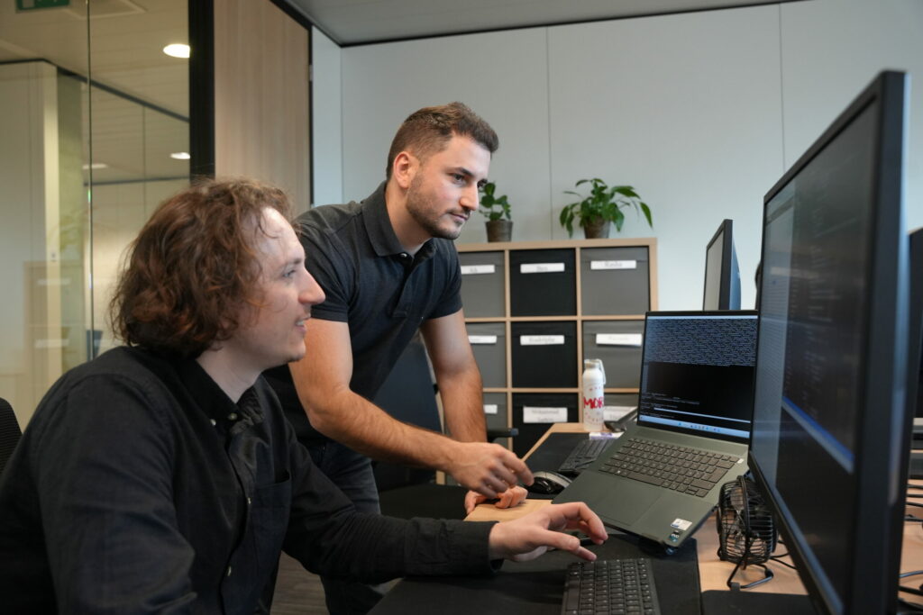 Twee ontwikkelaars werken aan een aangepaste applicatie in een modern kantoor.