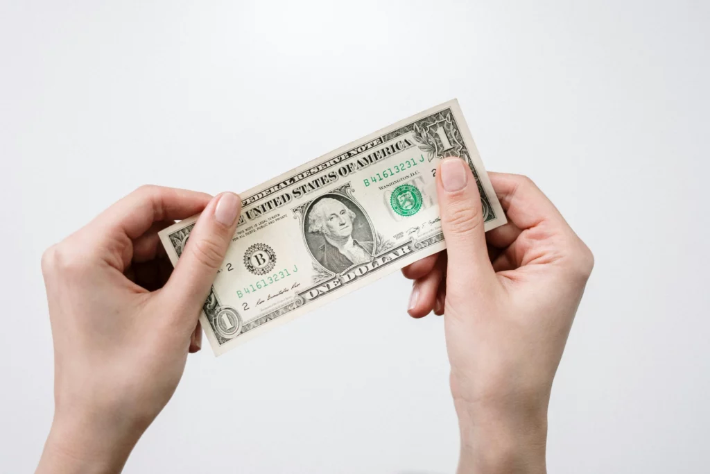 Deux mains tenant un billet d’un dollar américain.