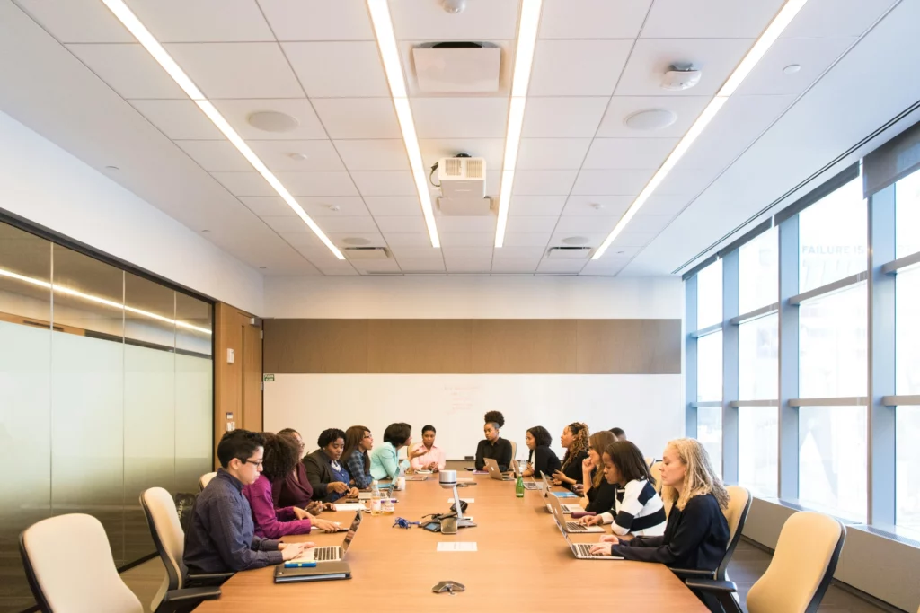 Collaborateurs en réunion dans une salle de conférence moderne - iterates Réunion d’équipe autour d’une grande table de conférence dans une salle lumineuse.