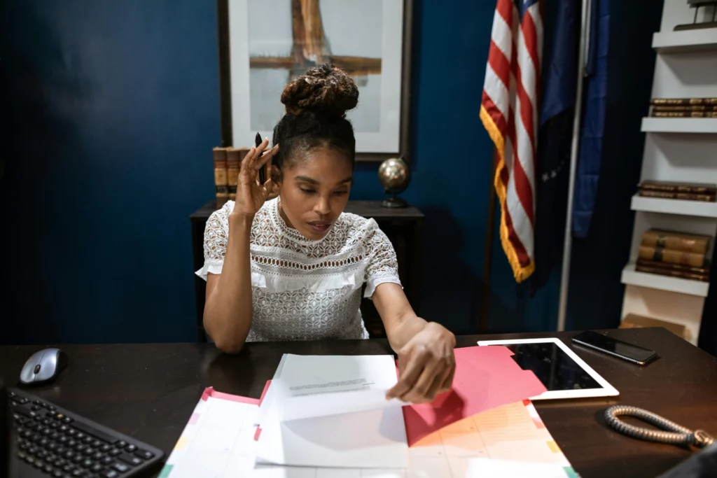 Professionnelle travaillant sur des dossiers administratifs - iterates Femme concentrée examinant des documents à son bureau dans un bureau professionnel.