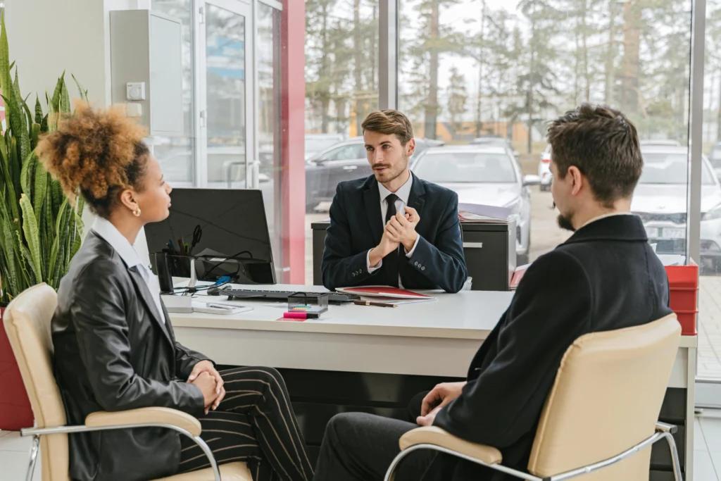 Trois professionnels en réunion dans un bureau moderne, discutant autour d’un bureau.