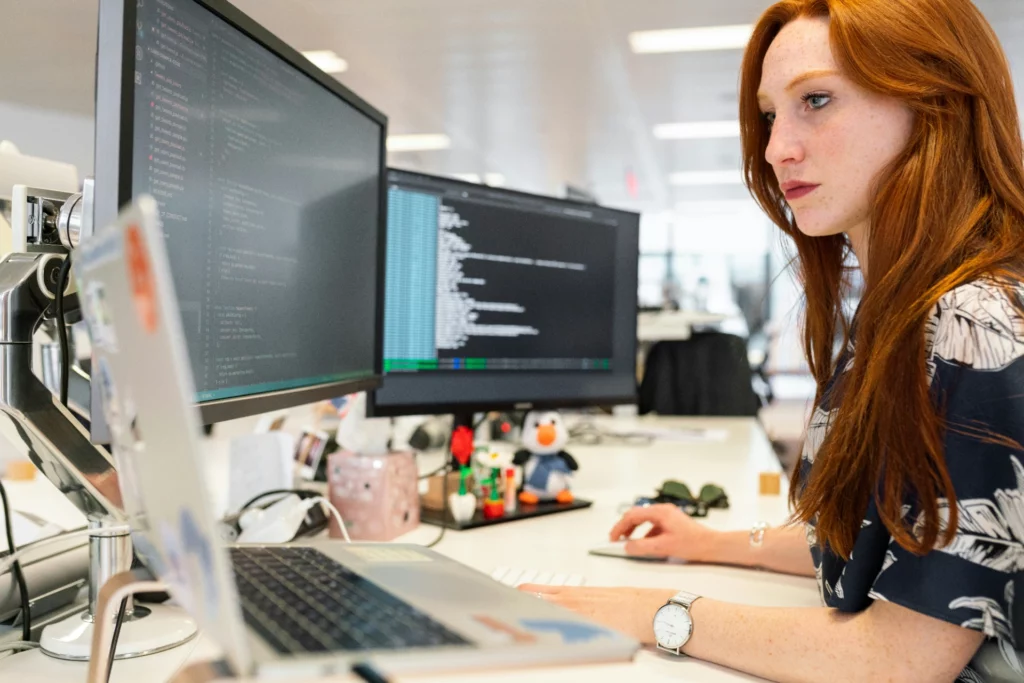 Ingénieure logiciel programmant sur un double écran en open space - iterates Développeuse concentrée travaillant sur deux écrans d’ordinateur.