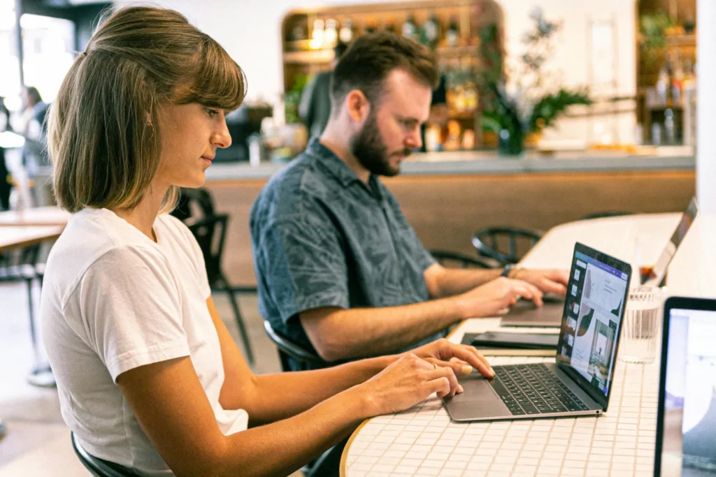 Deux professionnels travaillant sur des ordinateurs portables dans un espace de coworking.