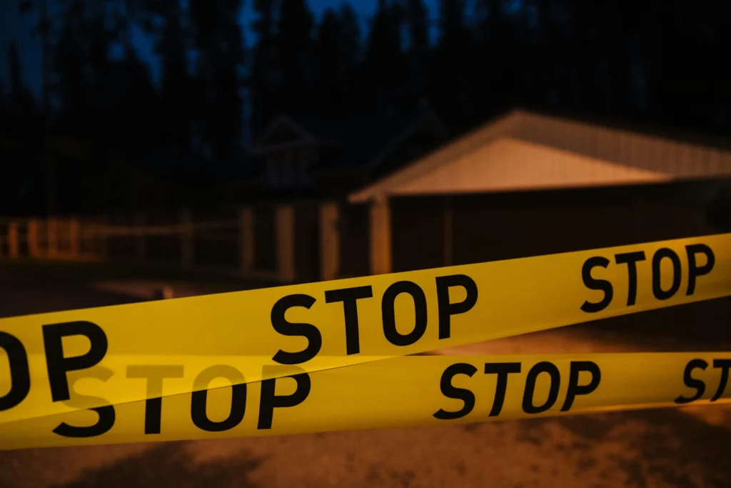 Ruban de signalisation jaune avec l’inscription « STOP » devant une maison la nuit.