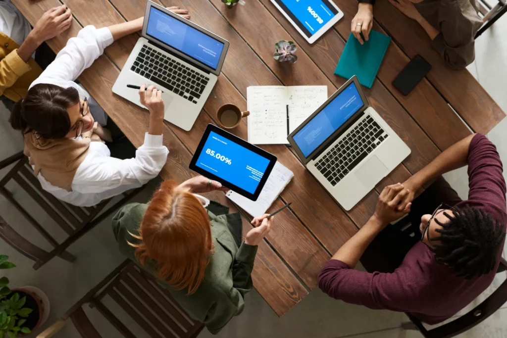 Analyse collaborative des indicateurs de performance - iterates Réunion d’équipe autour d’une table avec ordinateurs portables et tablette affichant des données de performance.