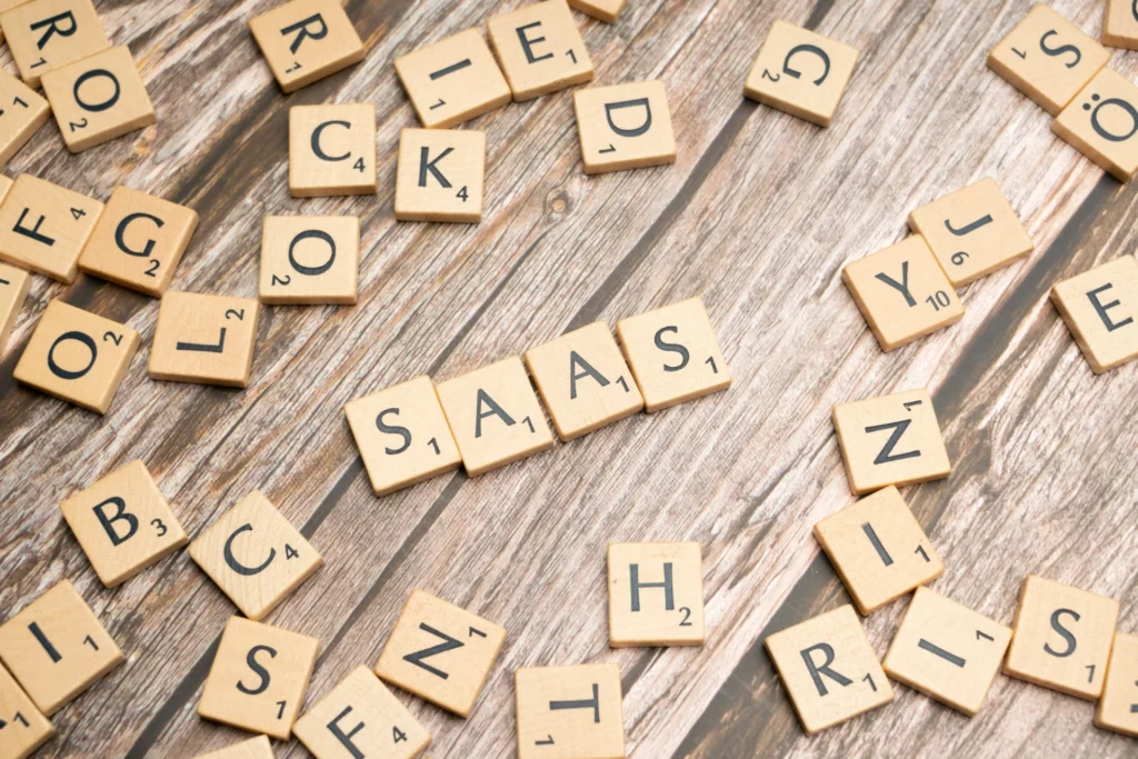 Le mot « SAAS » épelé avec des lettres en bois - iterates Lettres en bois formant le mot « SAAS » sur une table entourée d’autres lettres dispersées.