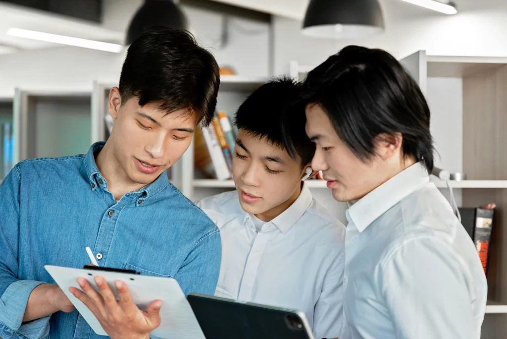 Trois jeunes professionnels collaborent sur un projet numérique avec une tablette et un carnet.