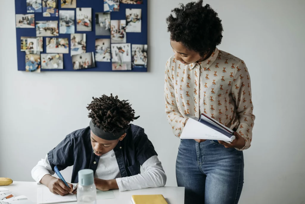 Soutien scolaire personnalisé en classe - iterates Une enseignante aide un élève à faire ses devoirs en classe.