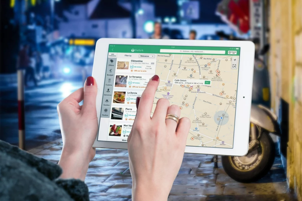 Personne utilisant une tablette pour rechercher des restaurants sur une carte interactive.