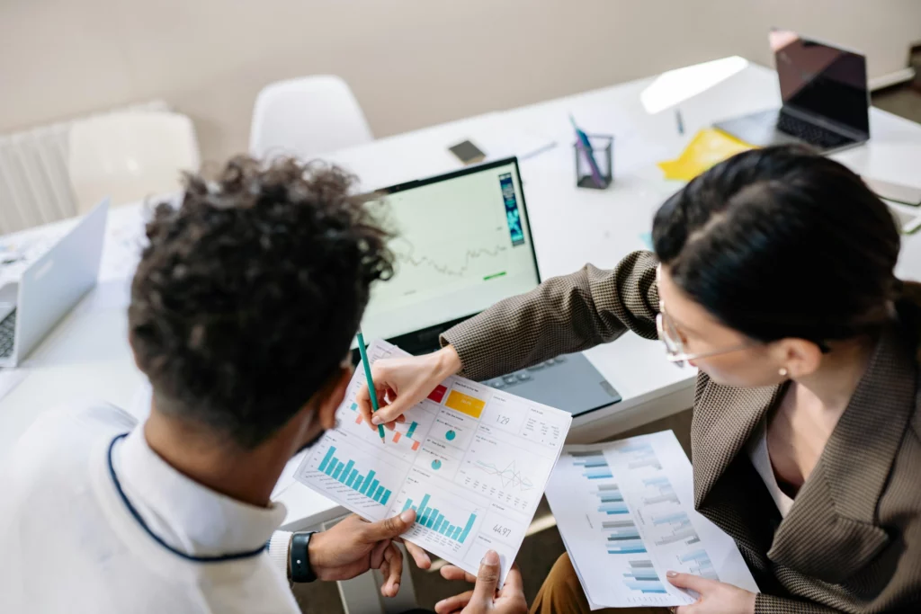 Deux collègues analysant des graphiques financiers et des données sur un ordinateur portable.