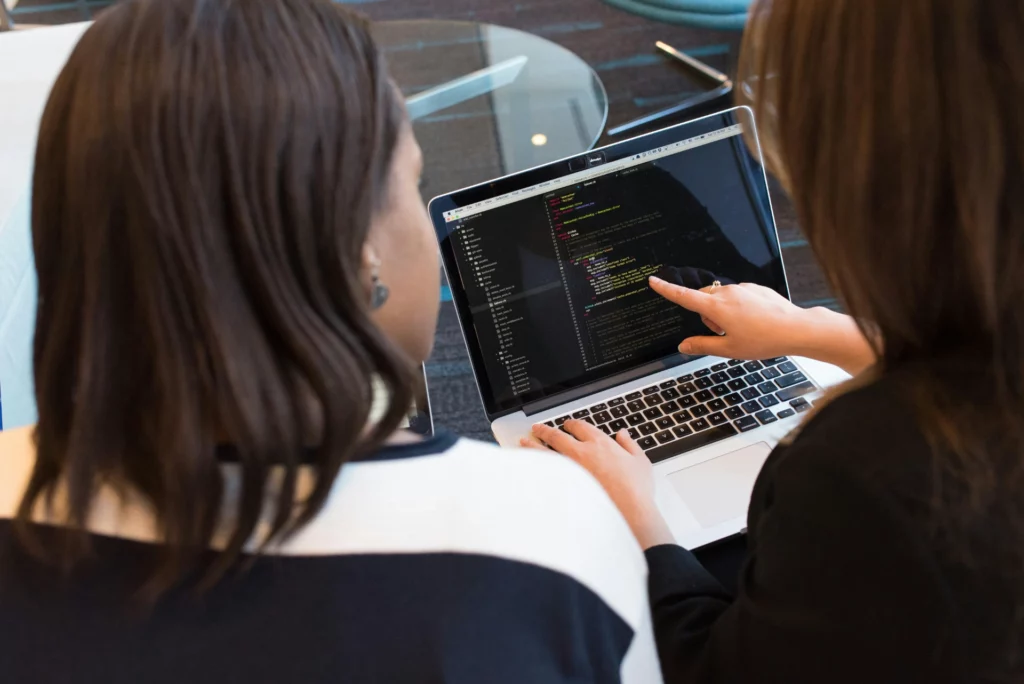 Deux personnes discutant de code informatique sur un ordinateur portable.