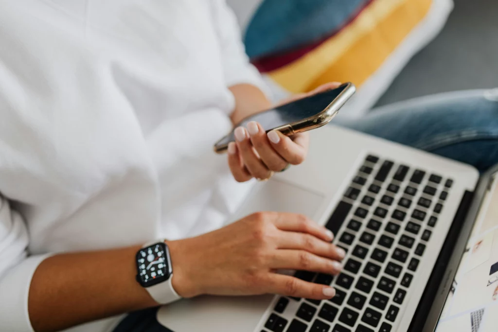 Travail multitâche entre smartphone et ordinateur portable - iterates Personne utilisant un ordinateur portable tout en tenant un smartphone.