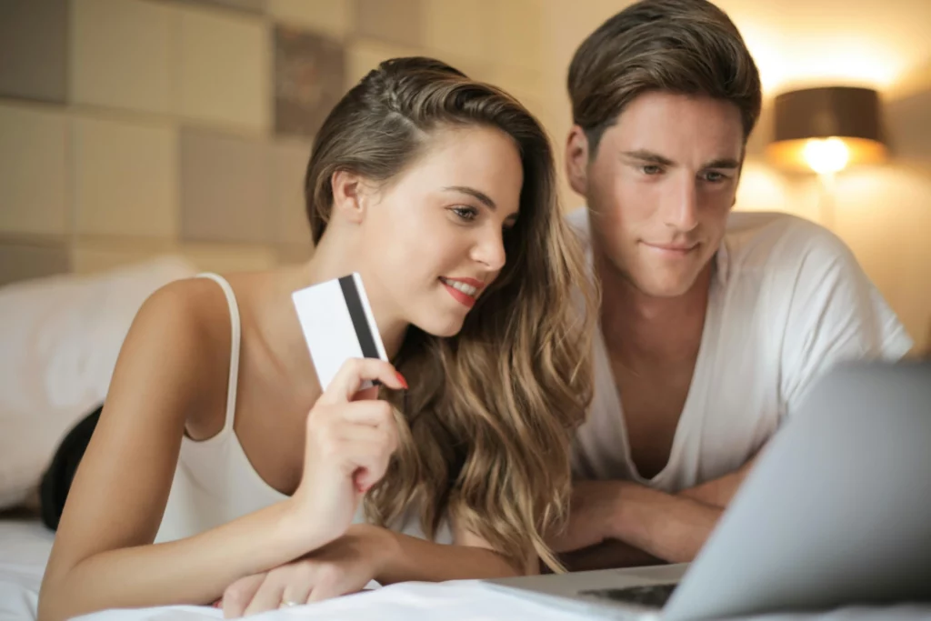 Couple souriant en train de faire du shopping en ligne depuis un ordinateur portable.