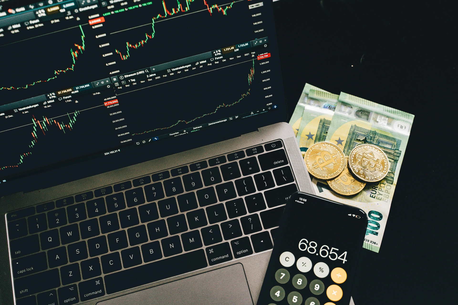 Financial analysis with cryptocurrency and calculations - iterates A laptop displaying stock charts, with physical currency and bitcoins sitting next to it, and a phone displaying a calculation.
