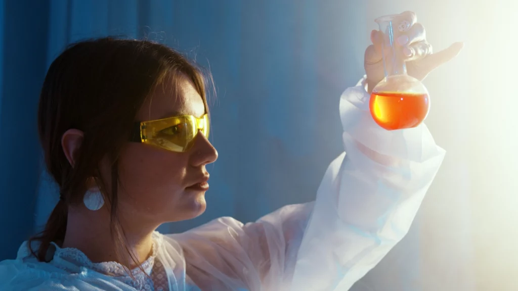Recherche scientifique et expertise - iterates Femme scientifique analysant un liquide orange dans un laboratoire.