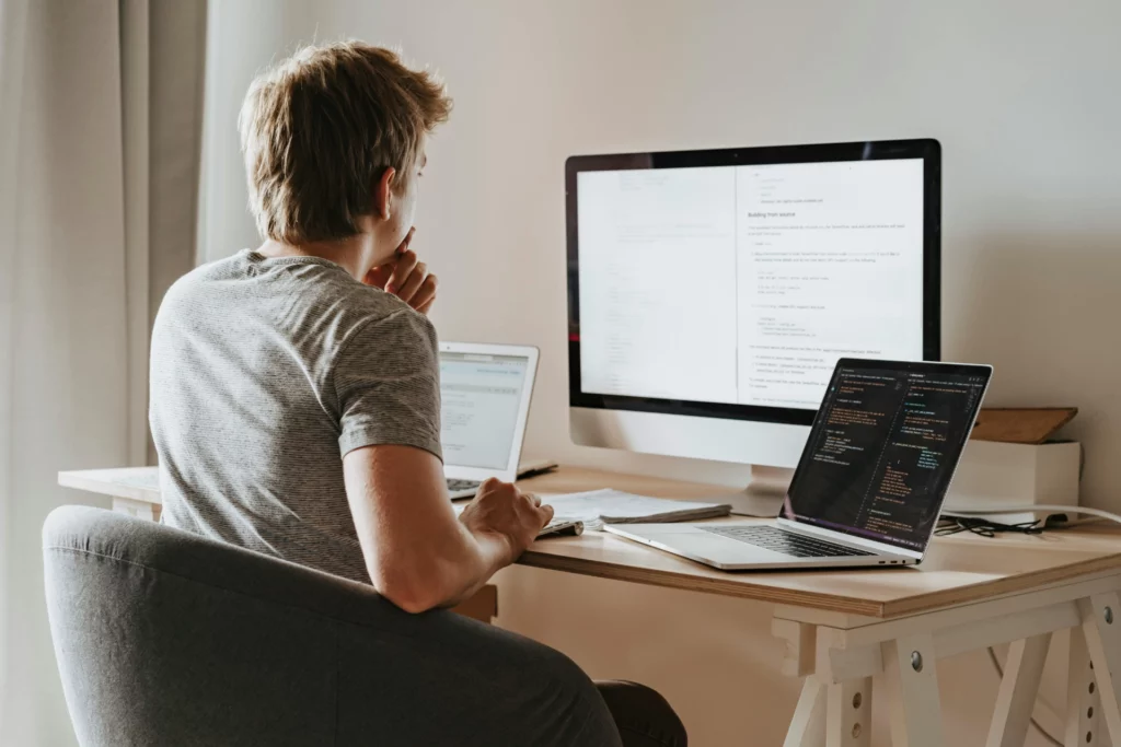 Développeur travaillant sur plusieurs écrans d’ordinateur dans un bureau à domicile.