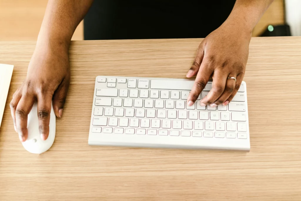 Travail numérique et gestion des données sensibles - iterates Mains d’une personne utilisant un clavier et une souris sur un bureau en bois clair.