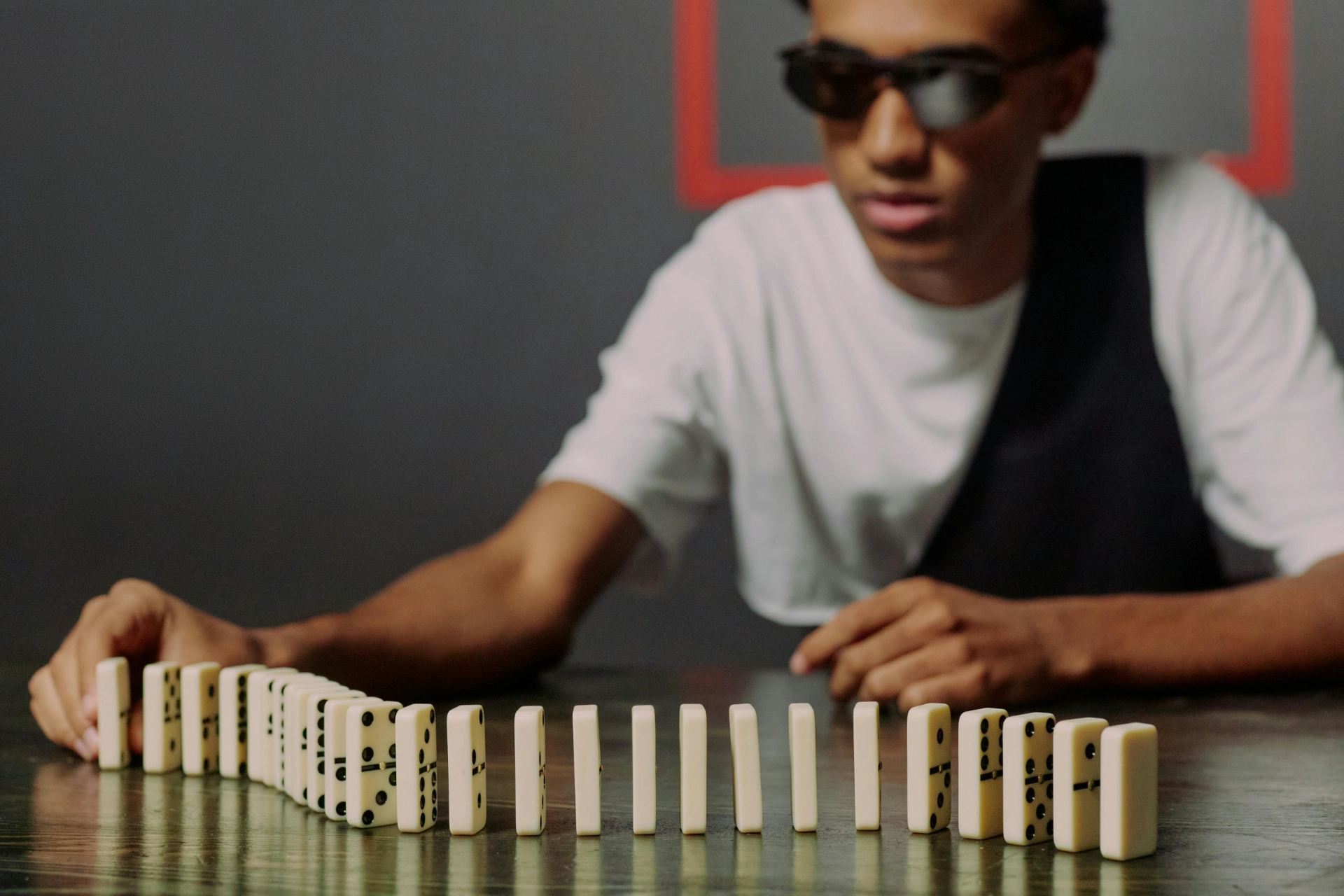 - iterates Young man preparing to knock down a row of dominoes.