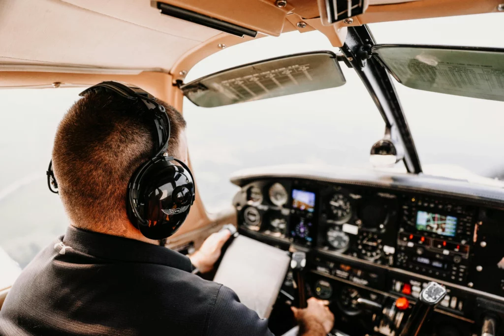 Sécurité numérique dans le secteur du transport aérien sous NIS2 - iterates Pilote dans le cockpit d’un avion en train de contrôler les instruments de navigation.