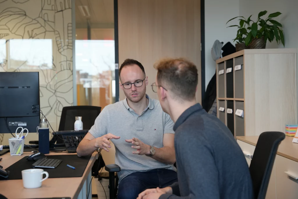 Deux collaborateurs en réunion de travail et conseil IT dans un bureau moderne à Bruxelles